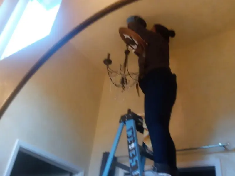 Electrician installing a chandelier in a Delhi Hills residence